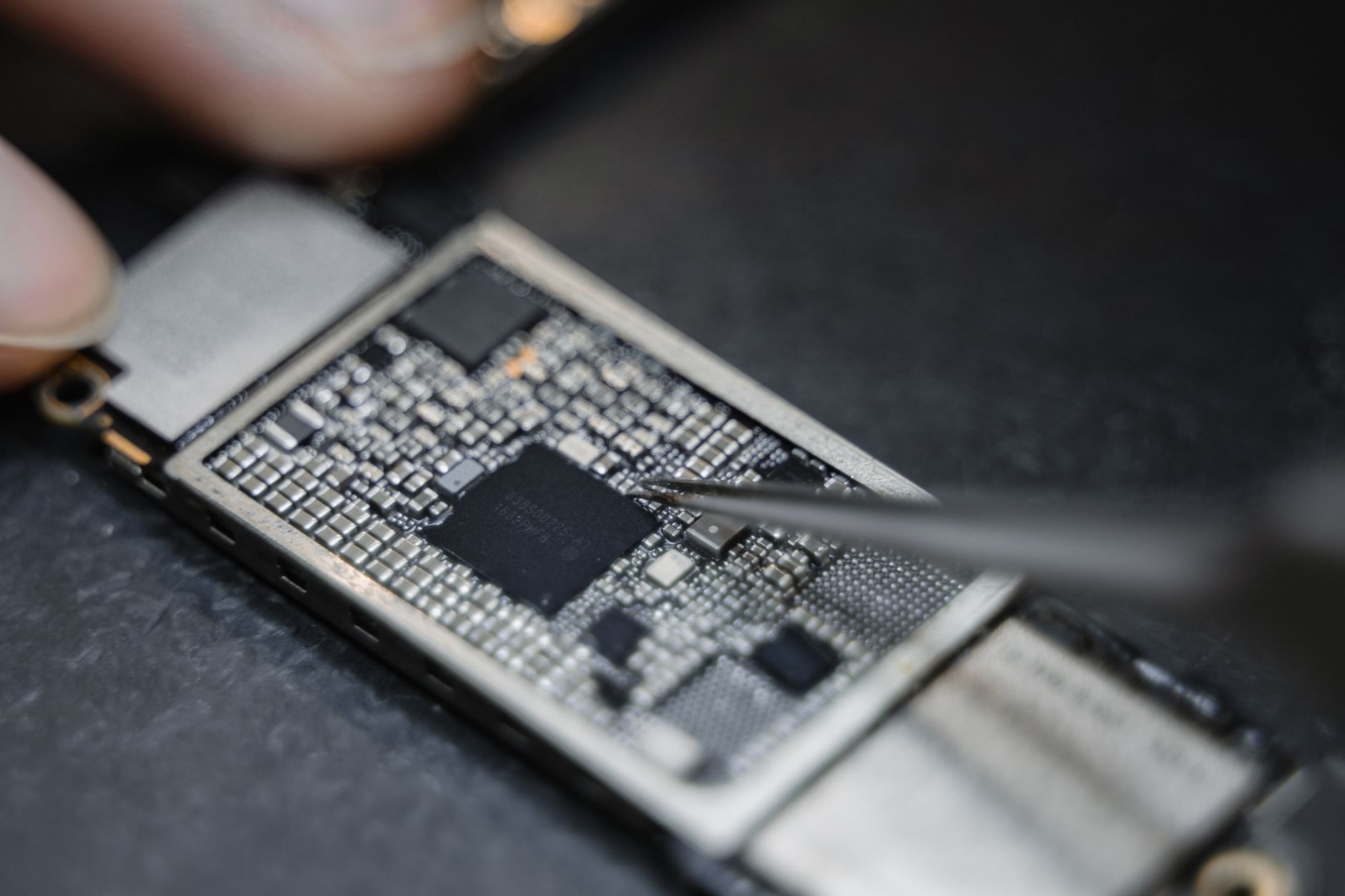 cách phân tần loa (crossover) - Detailed view of a technician using tweezers to fix an electronic circuit board.