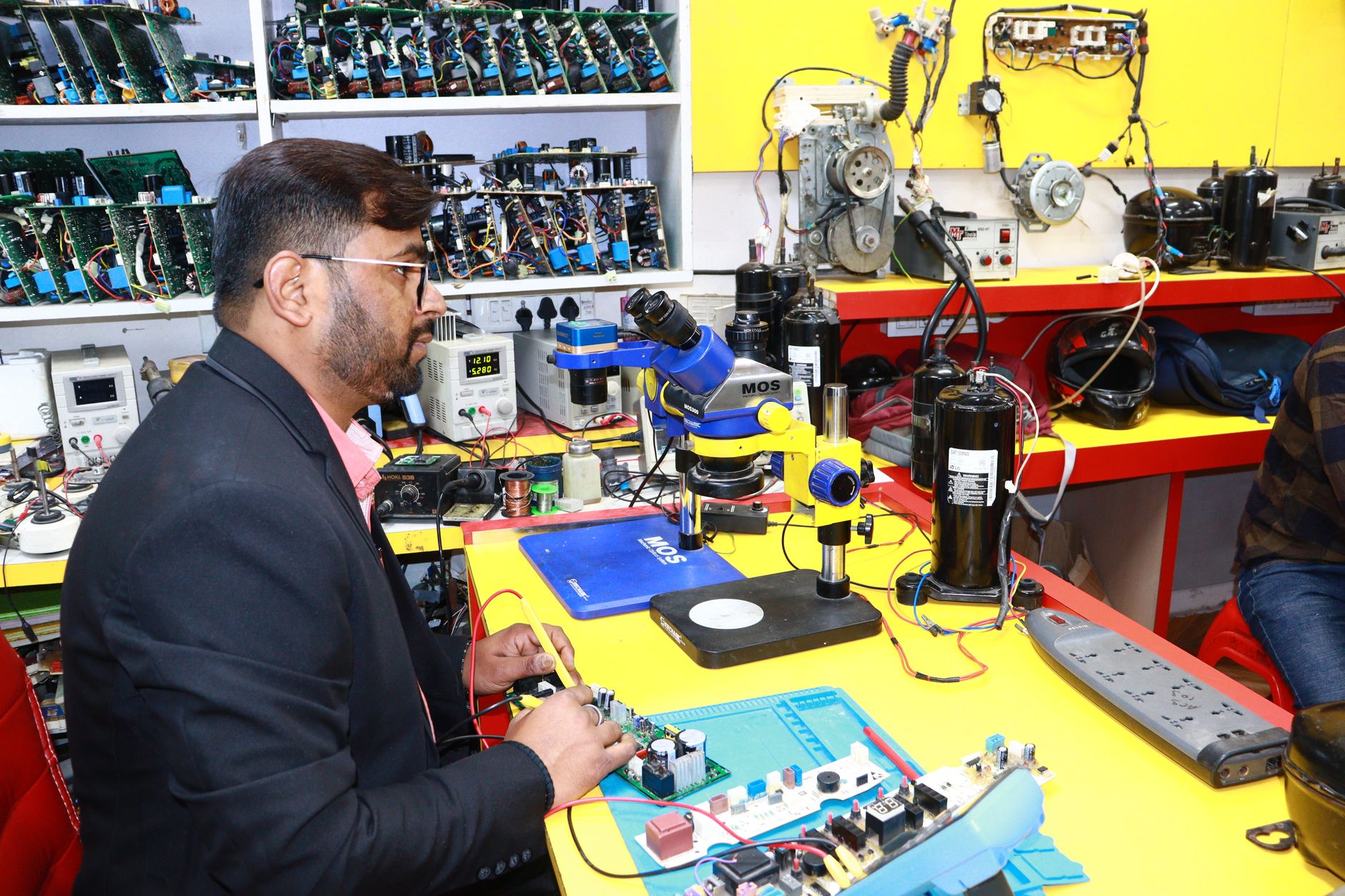 Cách lắp đặt dàn karaoke gia đình hoàn chỉnh - A man in Delhi working in an electronics lab with tools and components.