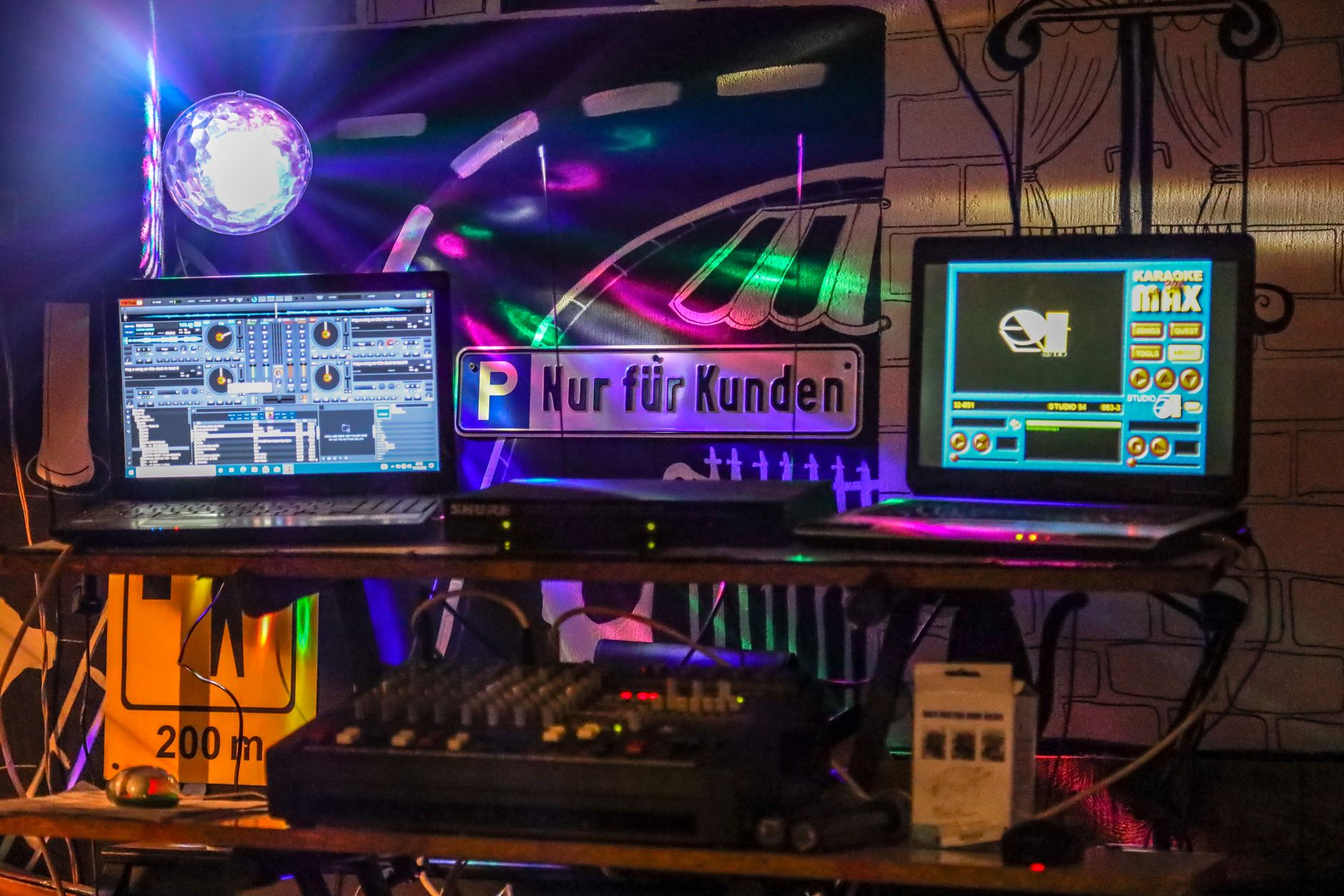 Hướng Dẫn Đấu Nối Dàn Karaoke Chuẩn Cho Người Mới - A dynamic DJ booth setup in a nightclub illuminated with colorful neon lights and bustling electronic equipment.
