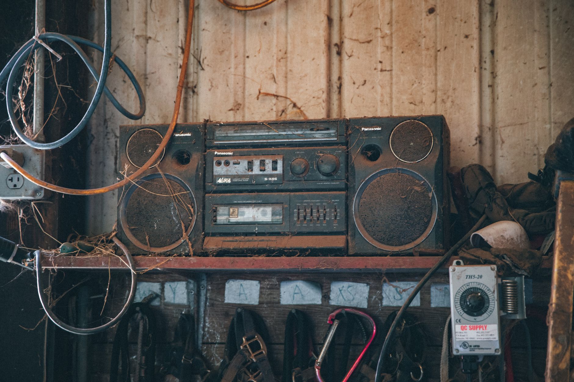 Setup âm thanh hội trường, sự kiện - Old fashioned obsolete compact stereo system covered with dust placed on shelf near wooden wall in workshop with tools and wires