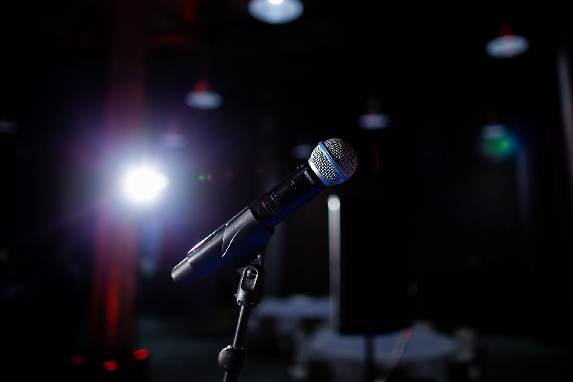 Cách Chọn Amply Phù Hợp Với Loa Karaoke (Theo Công Suất) - Microphone on a stage with spotlight, perfect for performance and public speaking themes.
