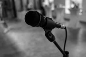 Cách Chọn Amply Phù Hợp Với Loa Karaoke (Theo Công Suất) - Detailed black and white close-up of a microphone in an indoor setting, capturing its texture.