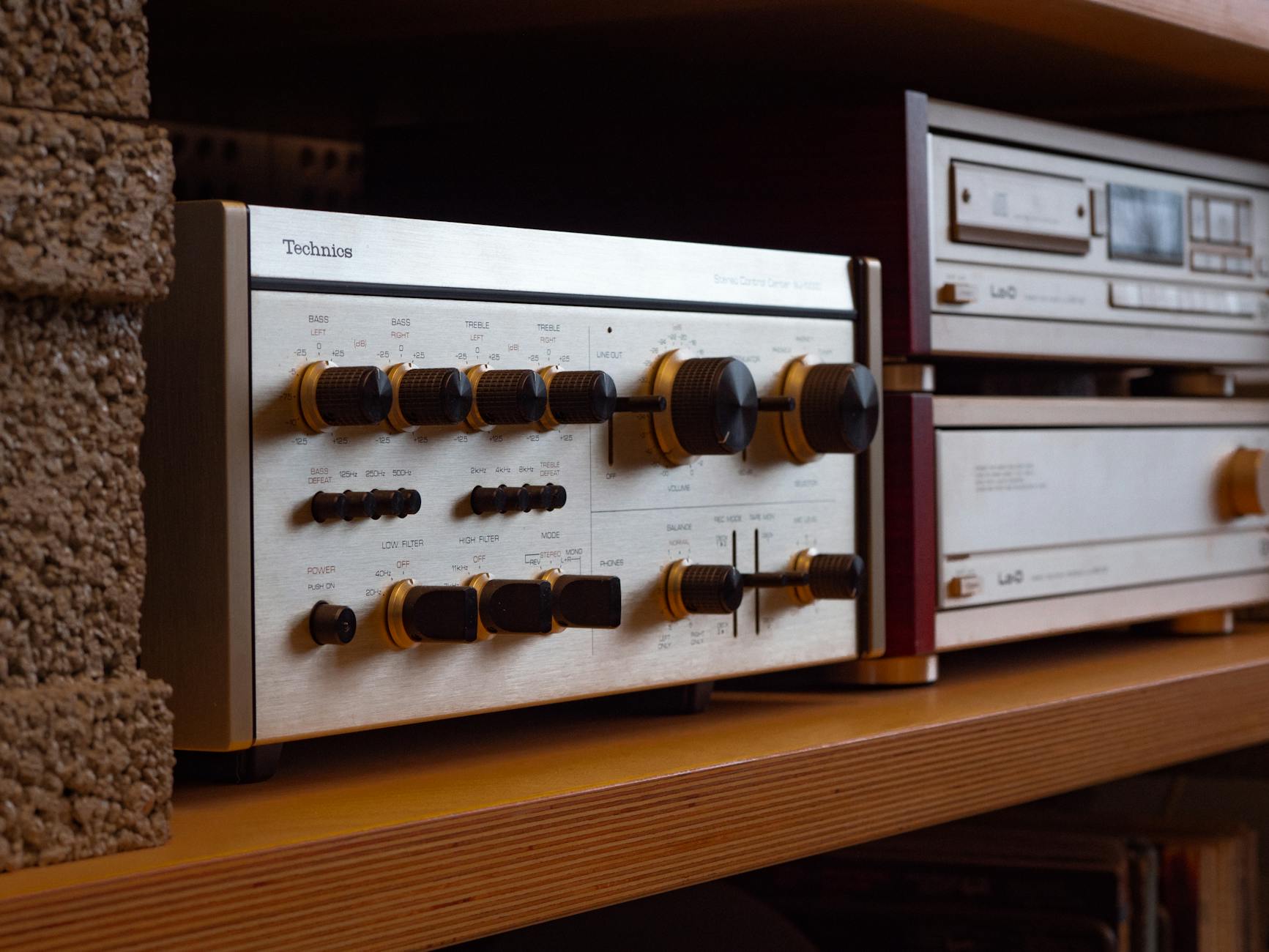 Amply Là Gì? Cấu Tạo & Nguyên Lý Hoạt Động Chi Tiết, amply là gì - Close-up of a retro stereo receiver with knobs on a shelf, exuding nostalgic vibes.