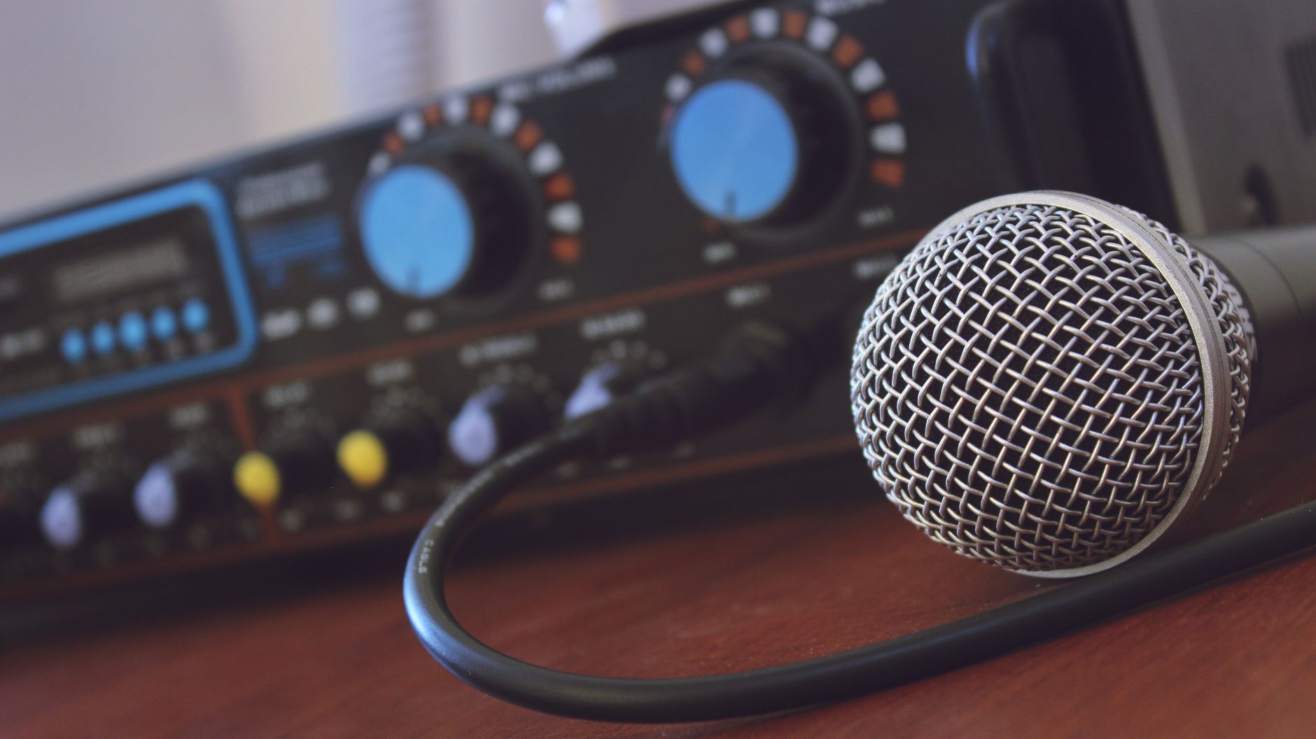 Amply Karaoke Loại Nào Tốt? Top Dòng Đáng Mua - Focused shot of a microphone with audio mixer in background, ideal for media or music themes.