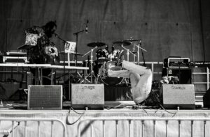 Cách Thay Côn Loa (Voice Coil) Bị Cháy - Dynamic monochrome image capturing a live stage performance with musicians and equipment.