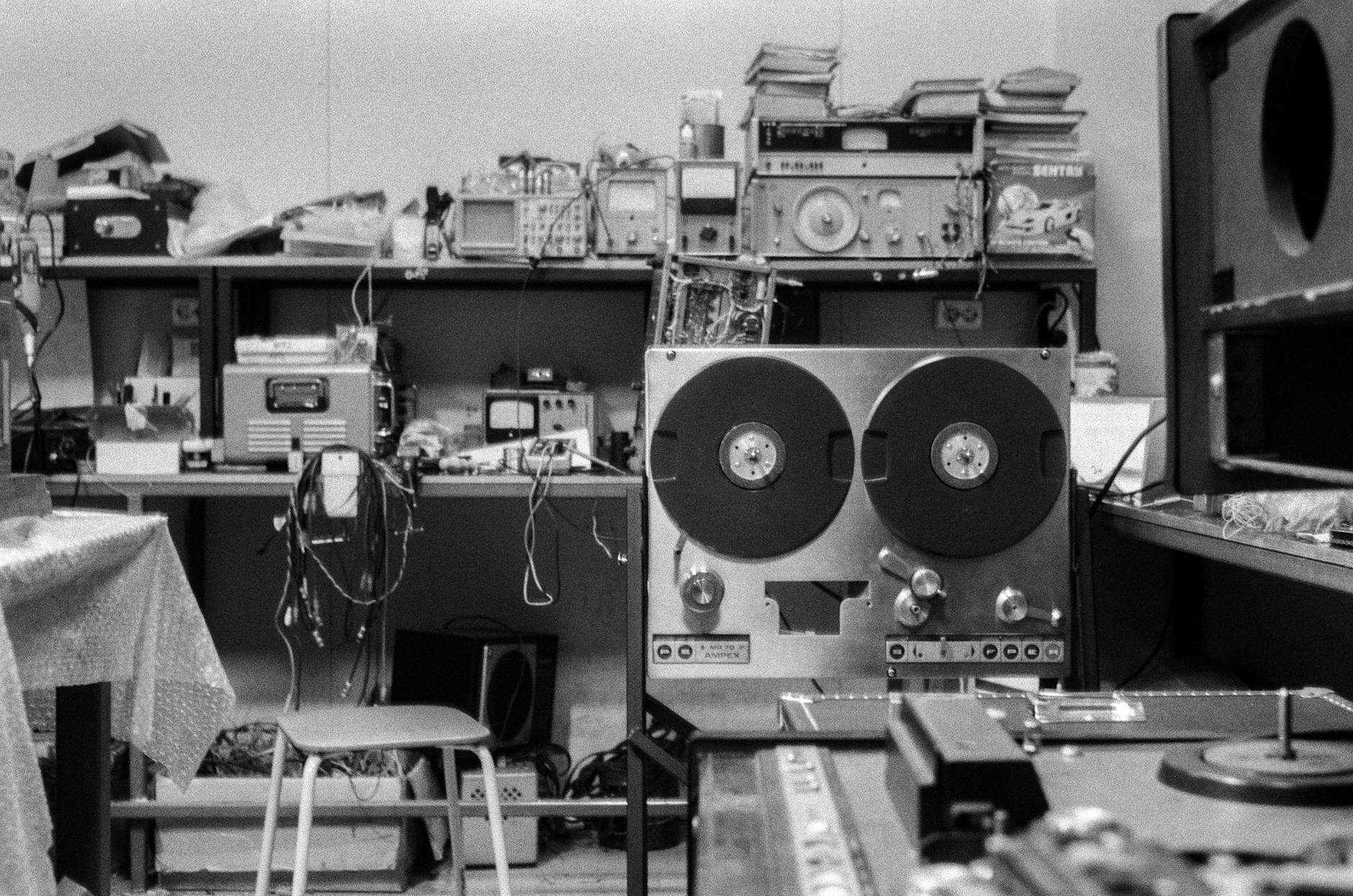 Hướng Dẫn Phối Ghép Amply Với Loa Đúng Trở Kháng - Black and white photo of a nostalgic audio repair shop featuring a reel-to-reel tape machine and various equipment.