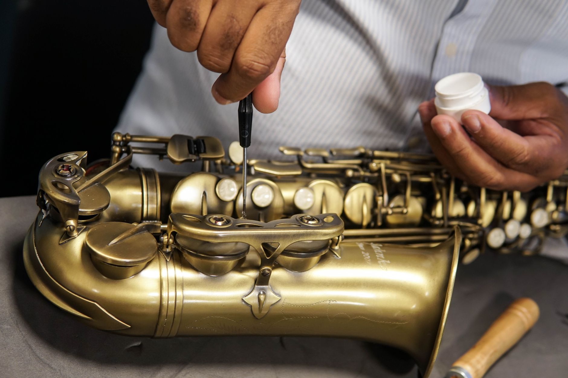 Amply Là Gì? Cấu Tạo & Nguyên Lý Hoạt Động Chi Tiết, amply là gì - A skilled technician repairing a saxophone, showcasing craftsmanship and expertise in musical instrument maintenance.