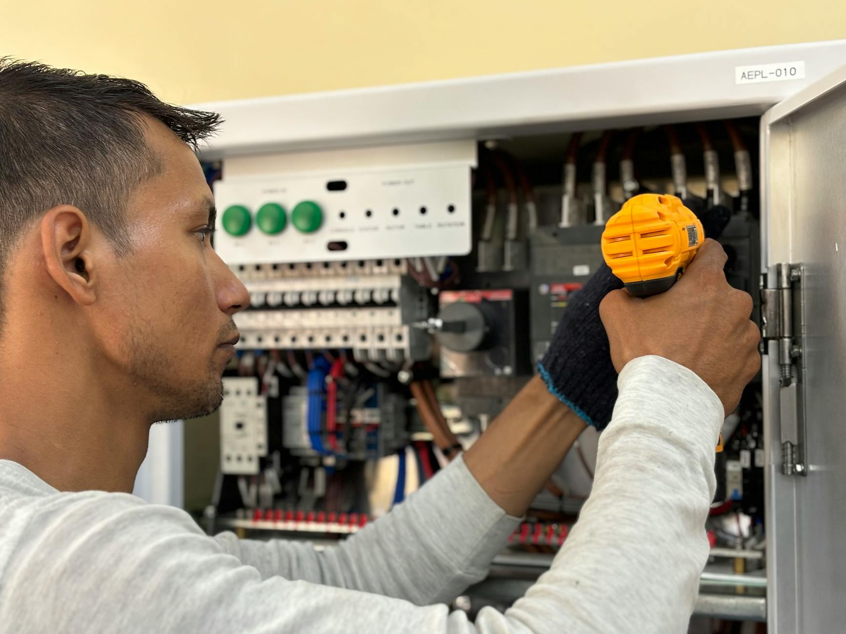 Amply Karaoke Loại Nào Tốt? Top Dòng Đáng Mua - Skilled electrician using a drill to repair electrical equipment indoors. Focus on precision and safety.