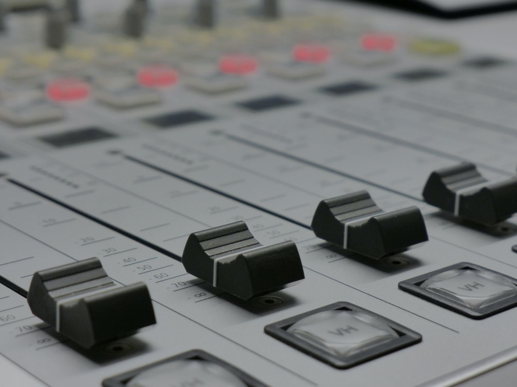 Tần số âm thanh là gì (Hz, dải bass-mid-treble) - Detailed view of audio mixer sliders in a recording studio setting.