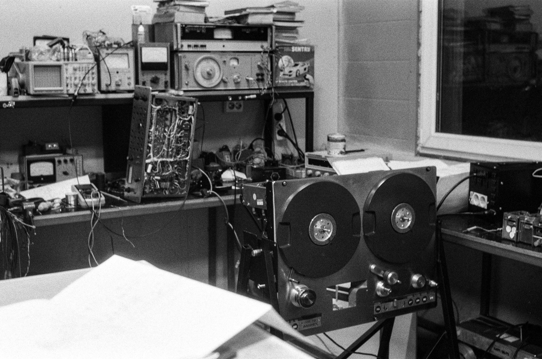 cách phân tần loa (crossover) - Black and white photo of vintage audio repair shop with magnetic tape equipment and electronics.
