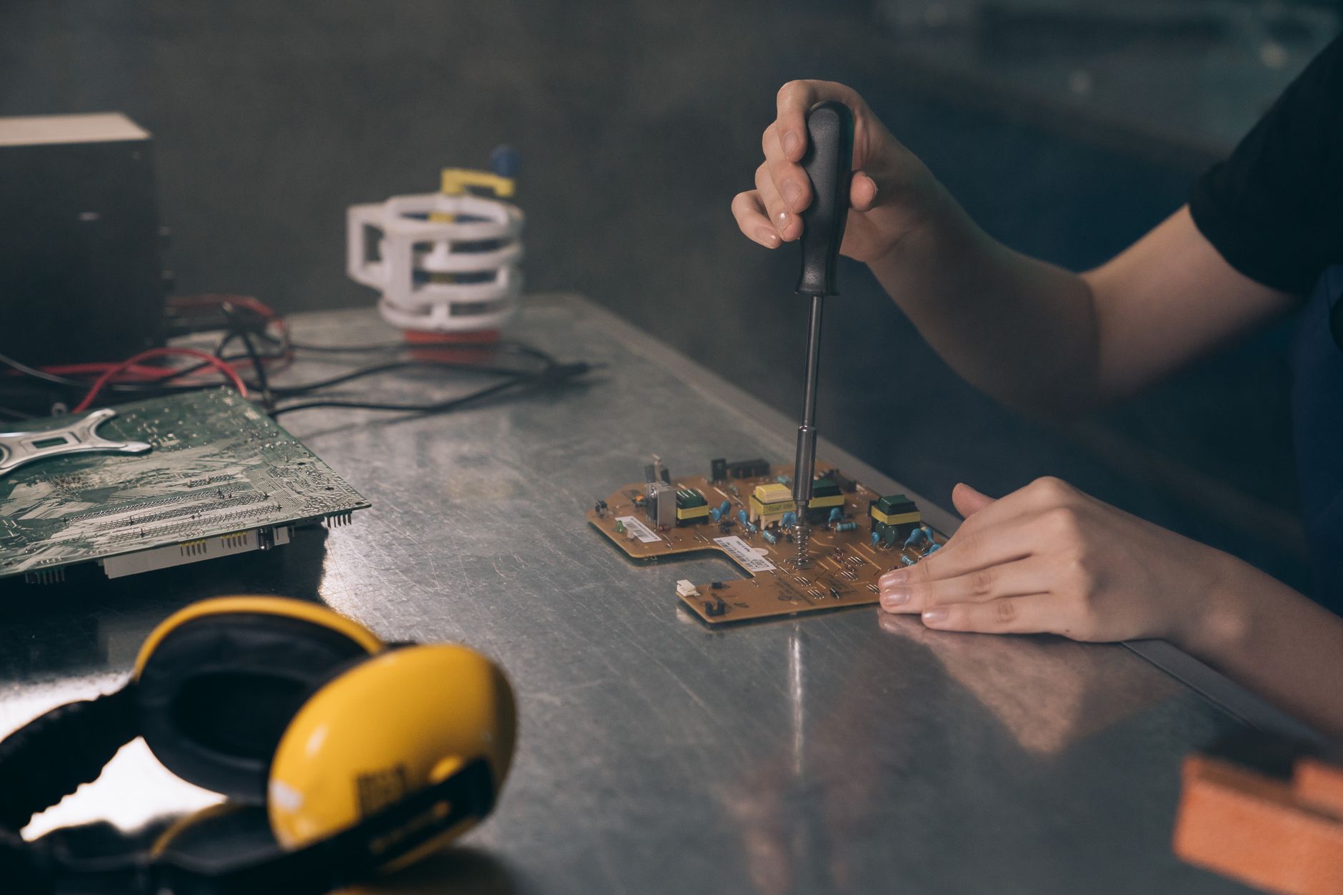 Âm thanh nhà thờ, chùa - Close-up of hands working on electronic circuit board in workshop.