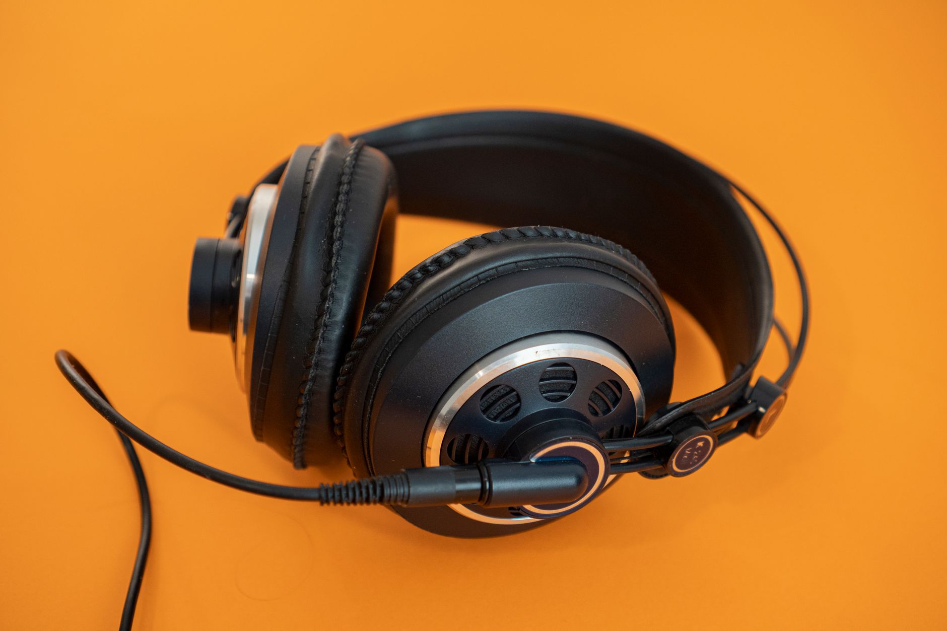 Các loại dây loa, cách chọn tiết diện dây - Close-up of professional headphones on a vivid orange background, ideal for audio and tech concepts.