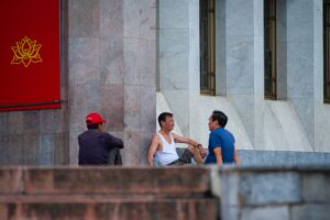 Hướng Dẫn Phối Ghép Amply Với Loa Đúng Trở Kháng - Three men engage in relaxed conversation outside a historical building in Hanoi, Vietnam.