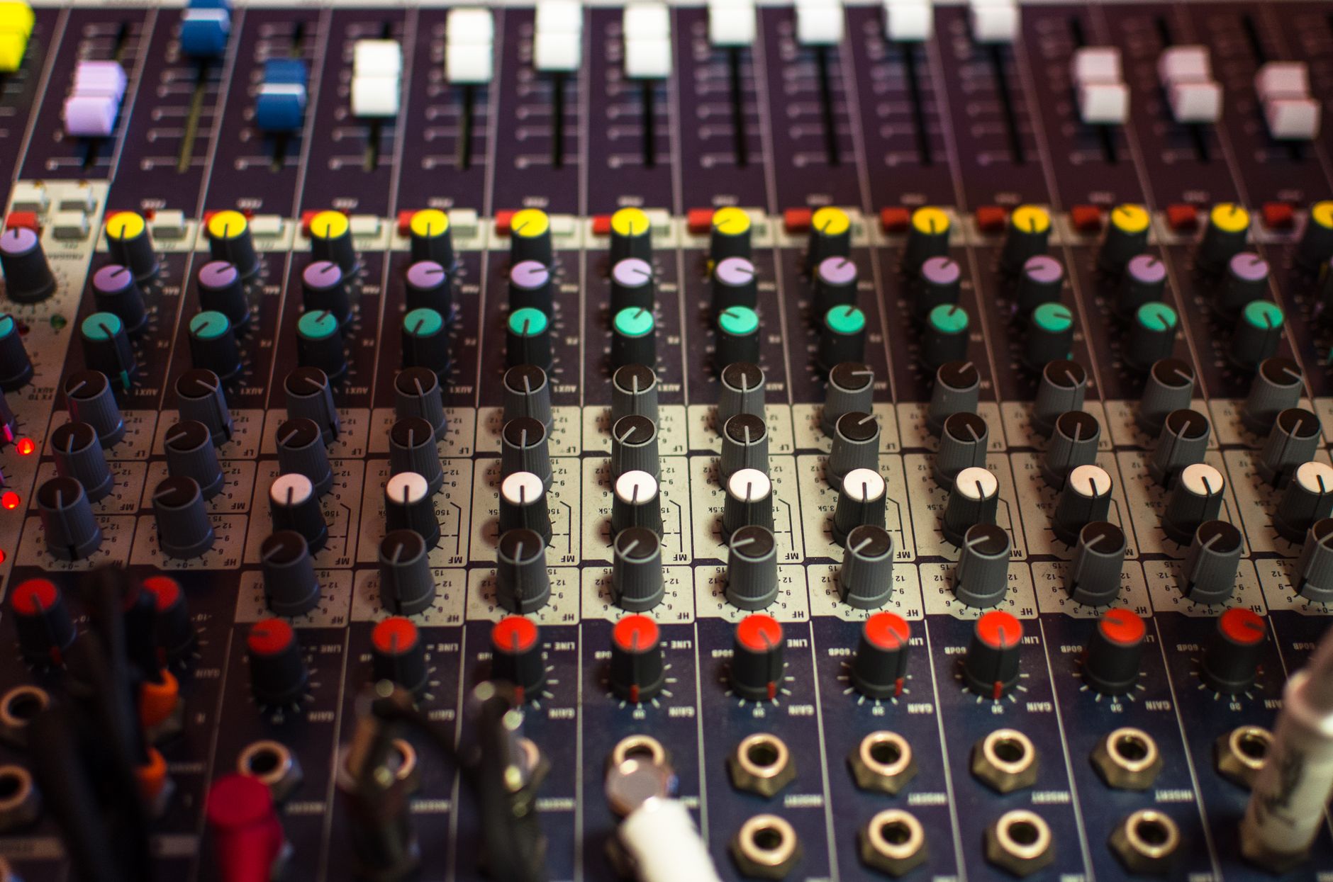 Cục Đẩy Nhảy Đèn Đỏ (Protect) – Nguyên Nhân - Detailed view of a professional audio mixing console with multicolored knobs in a studio setting.