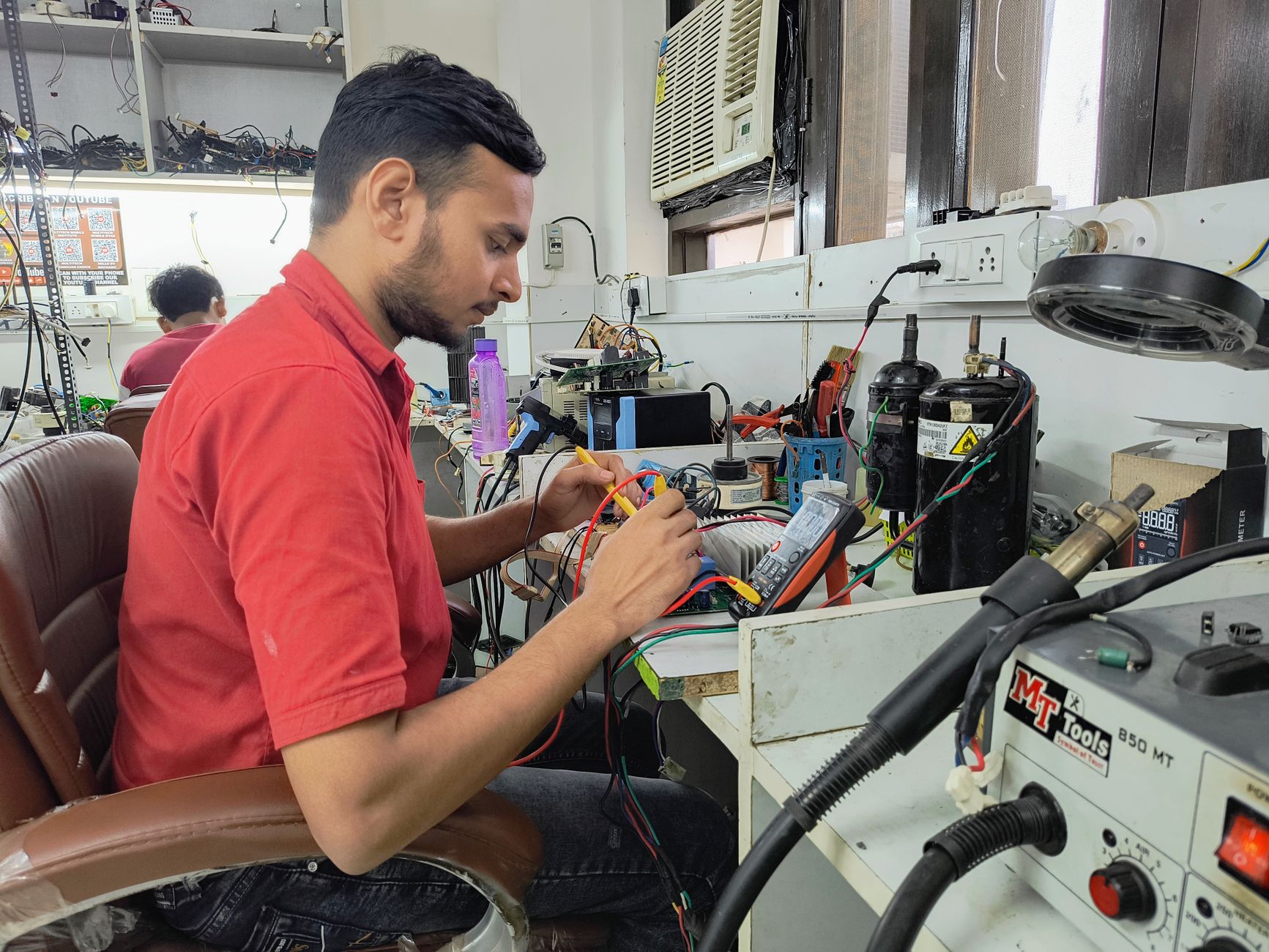 Cách Thay Côn Loa (Voice Coil) Bị Cháy - A young technician repairing electronics at a workshop. Focus on concentration and skill.