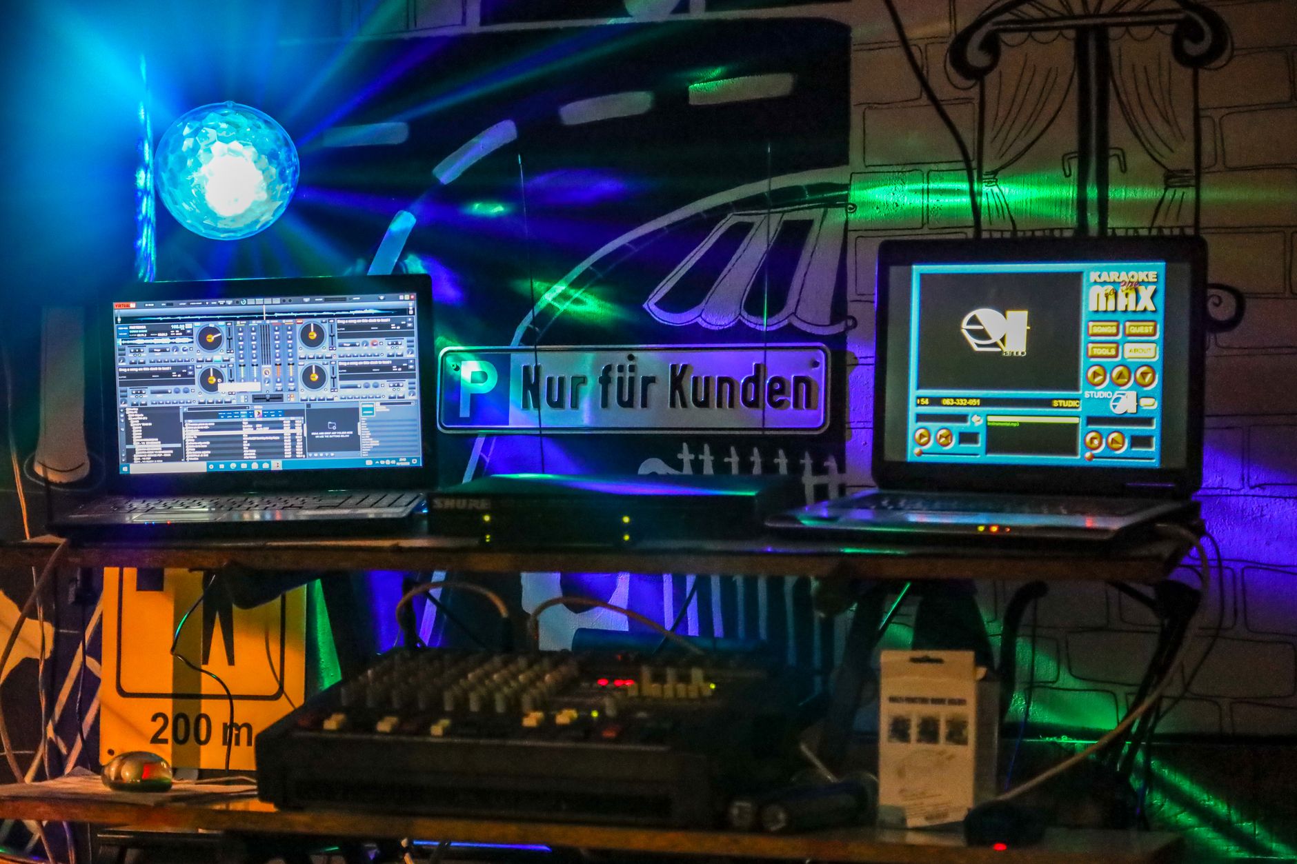 Cách Chọn Amply Phù Hợp Với Loa Karaoke (Theo Công Suất) - Vibrant DJ setup featuring laptops and a colorful disco light, perfect for nightlife scenes.