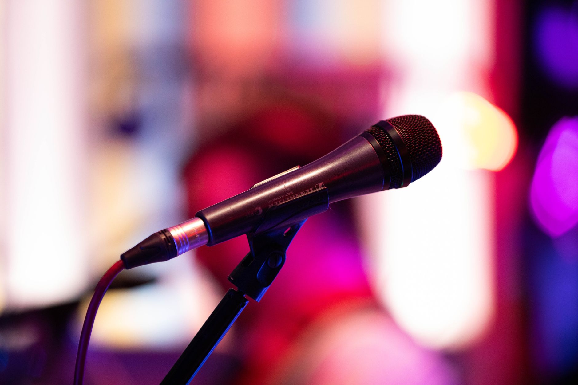 Hướng Dẫn Đấu Nối Dàn Karaoke Chuẩn Cho Người Mới - Close-up shot of a microphone on stage with colorful background bokeh, capturing live performance ambiance.