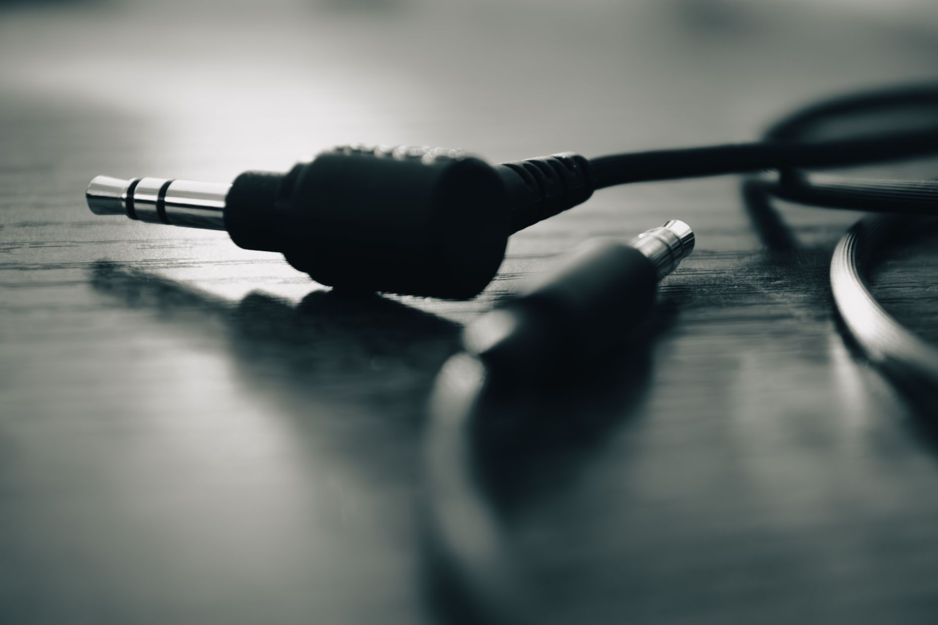 Cách chọn jack, đầu nối âm thanh - Black and white close-up of an audio jack on a wooden table.