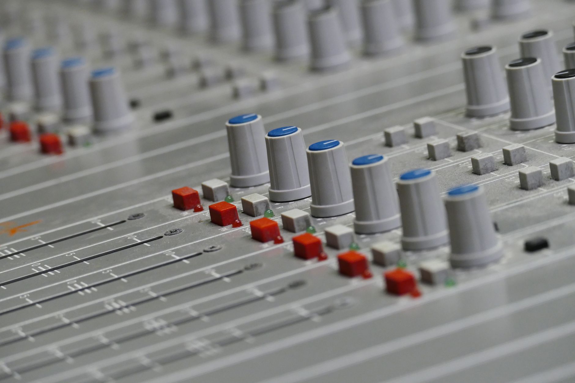 amply bị phù tụ - Detailed close-up of an audio mixer with colorful knobs and sliders in a recording studio.