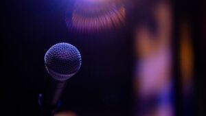 Ổn áp/lọc nguồn cho dàn âm thanh có cần không - A dramatic close-up of a microphone under a spotlight, evoking performance and music vibes.