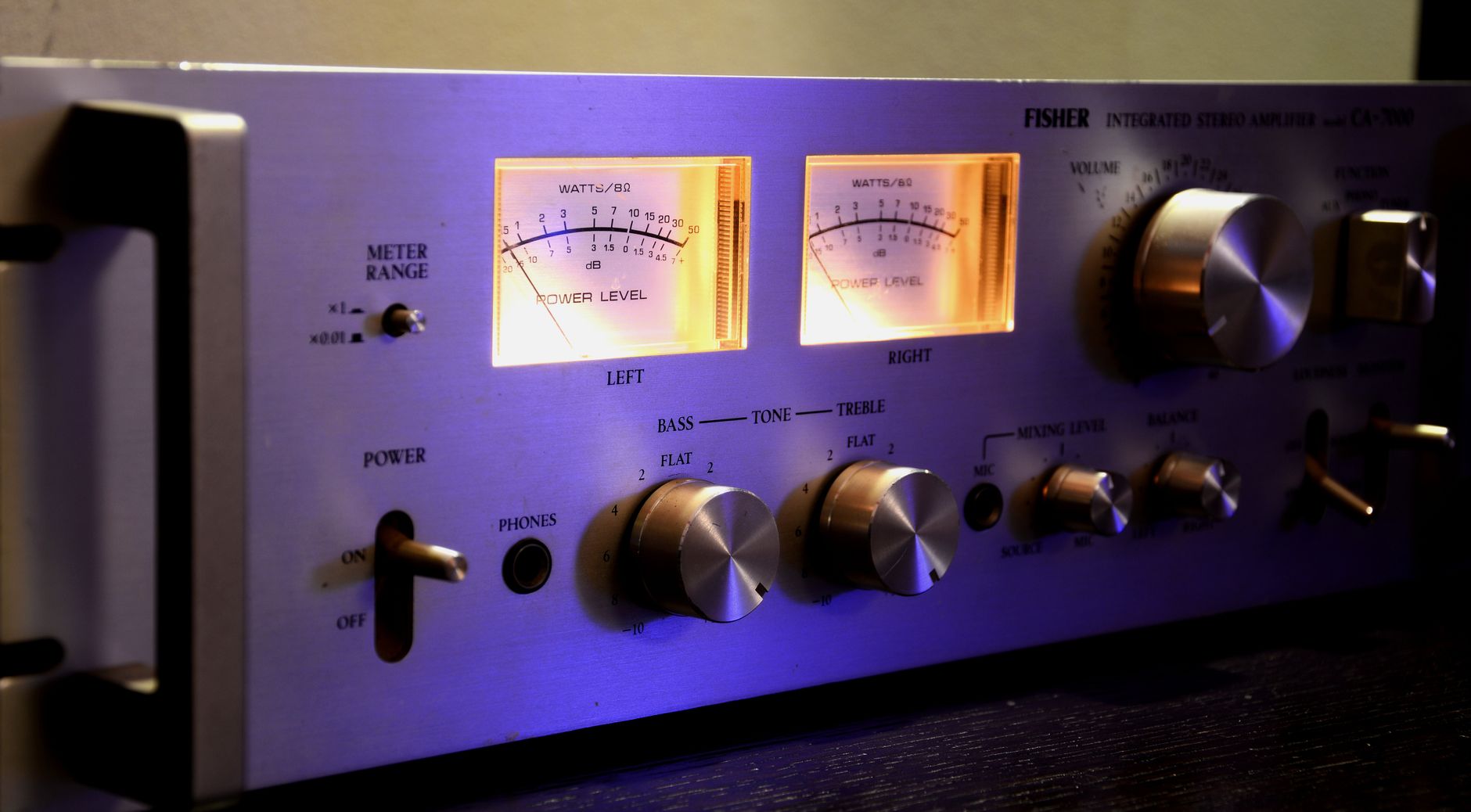 Cách Sử Dụng Amply Đúng Cách Để Bền & Hay - Close-up of a vintage stereo amplifier with glowing dials and controls.