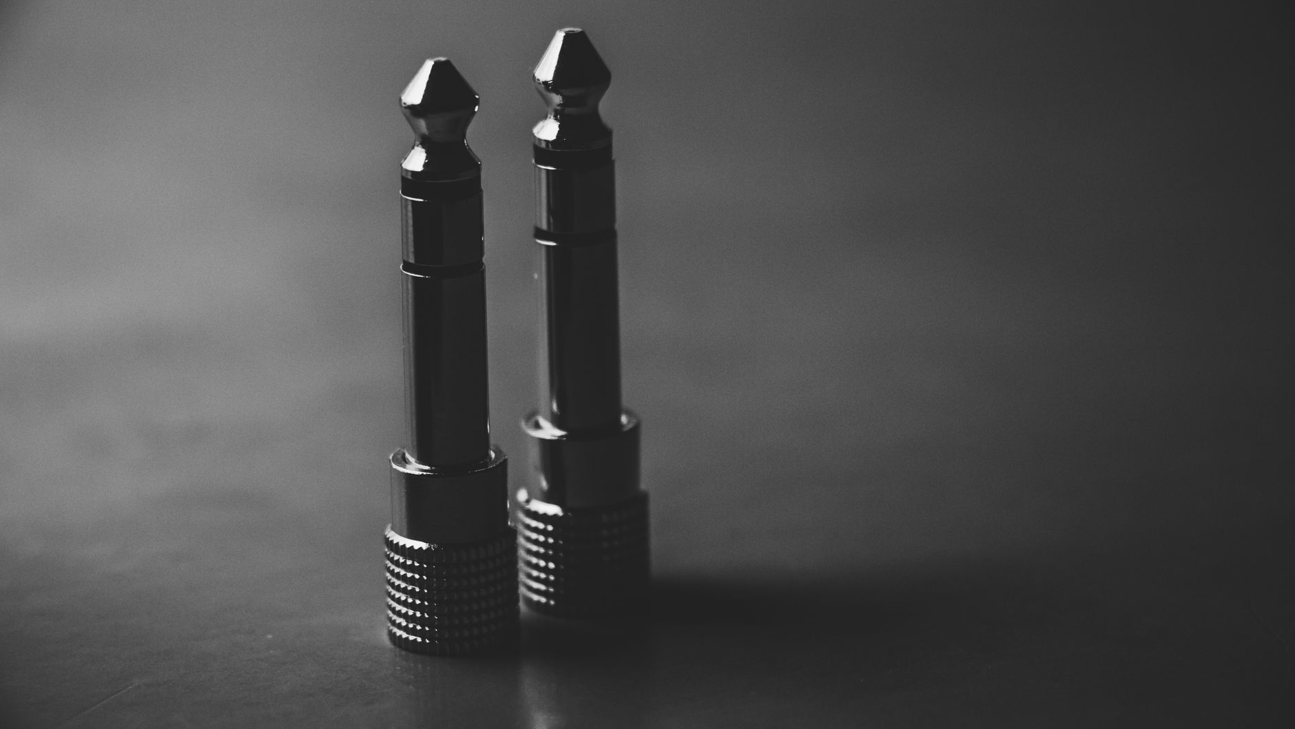 Cách chọn jack, đầu nối âm thanh - Black and white close-up of two audio jack plugs in a studio setting.