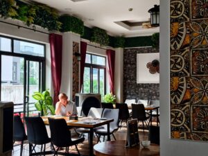 Setup Âm Thanh Quán Cafe, Nhà Hàng - Calm restaurant setting with an adult reading and green decor.