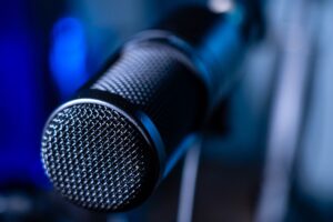 Sửa Micro Không Dây Bị Rè, Mất Sóng - Detailed close-up of a professional studio microphone with a blurred blue background.