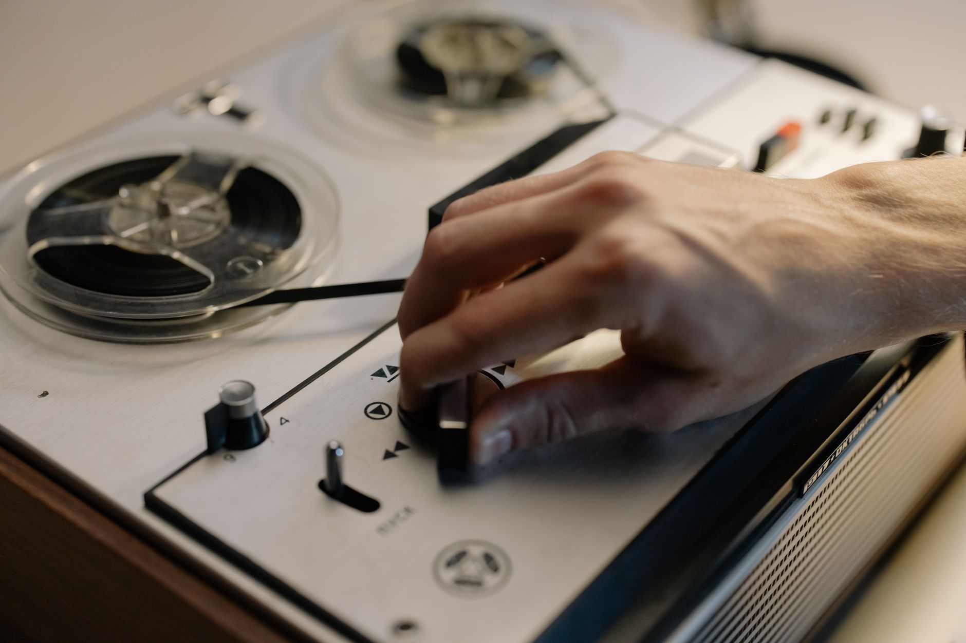 Stereo, Mono, Surround là gì - A detailed close-up of a hand adjusting controls on a vintage reel-to-reel tape recorder.