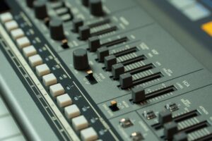 Tần số âm thanh là gì (Hz, dải bass-mid-treble) - Detailed view of a music mixing console with various sliders and buttons in a studio setting.