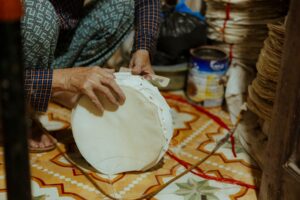 Thay Màng Loa, Ép Màng Loa – Quy Trình & Chi Phí - A skilled artisan carefully crafts handmade paper in a vibrant indoor setting.