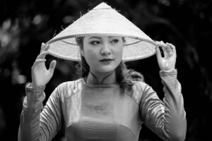 Thay Sò Công Suất Amply – Quy Trình & Chi Phí - Black and white portrait of a woman wearing a traditional Vietnamese conical hat outdoors.