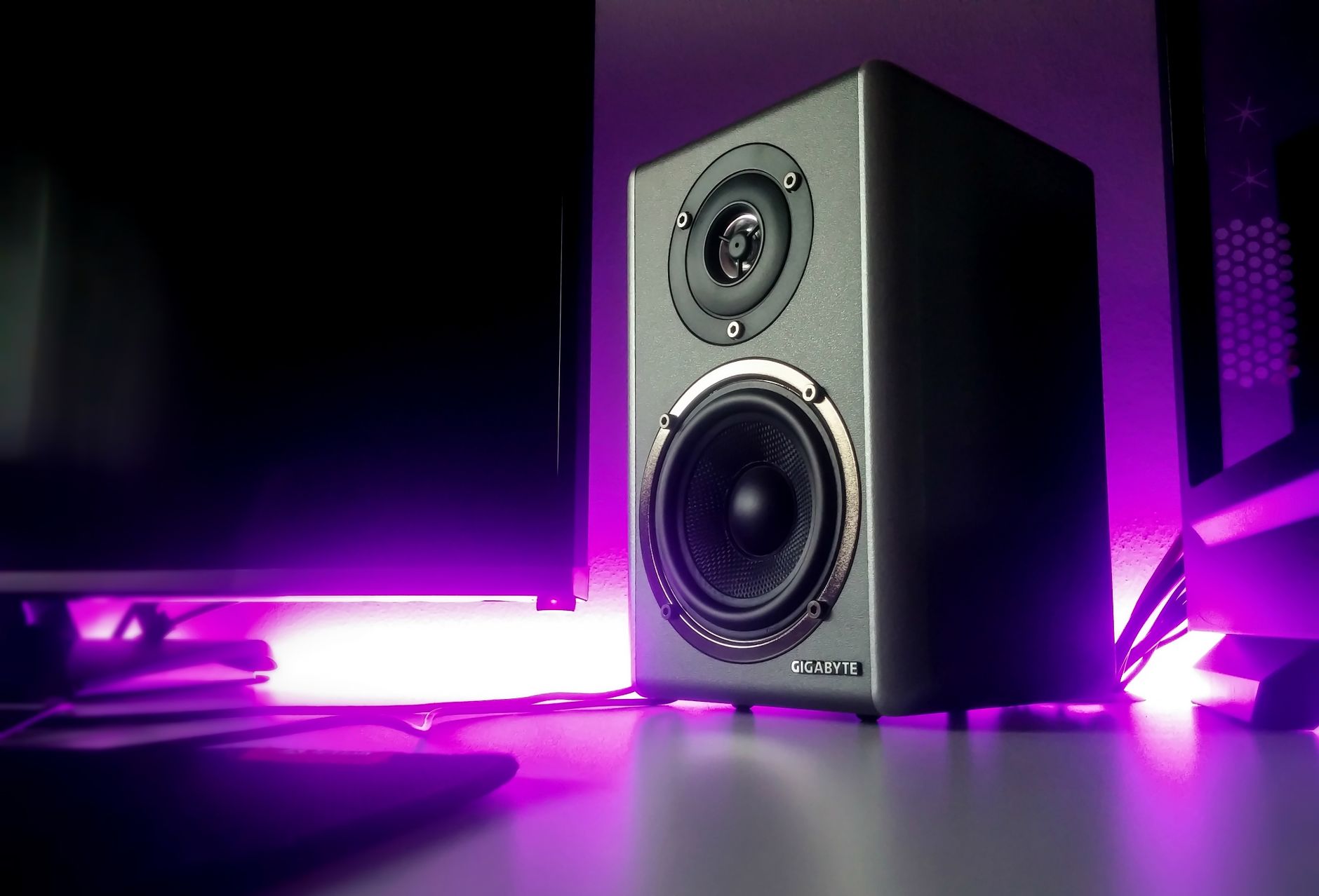 Amply Và Cục Đẩy Khác Nhau Như Thế Nào? Nên Chọn Loại Nào? - High-quality speaker setup with vibrant purple lighting in a modern studio setting.