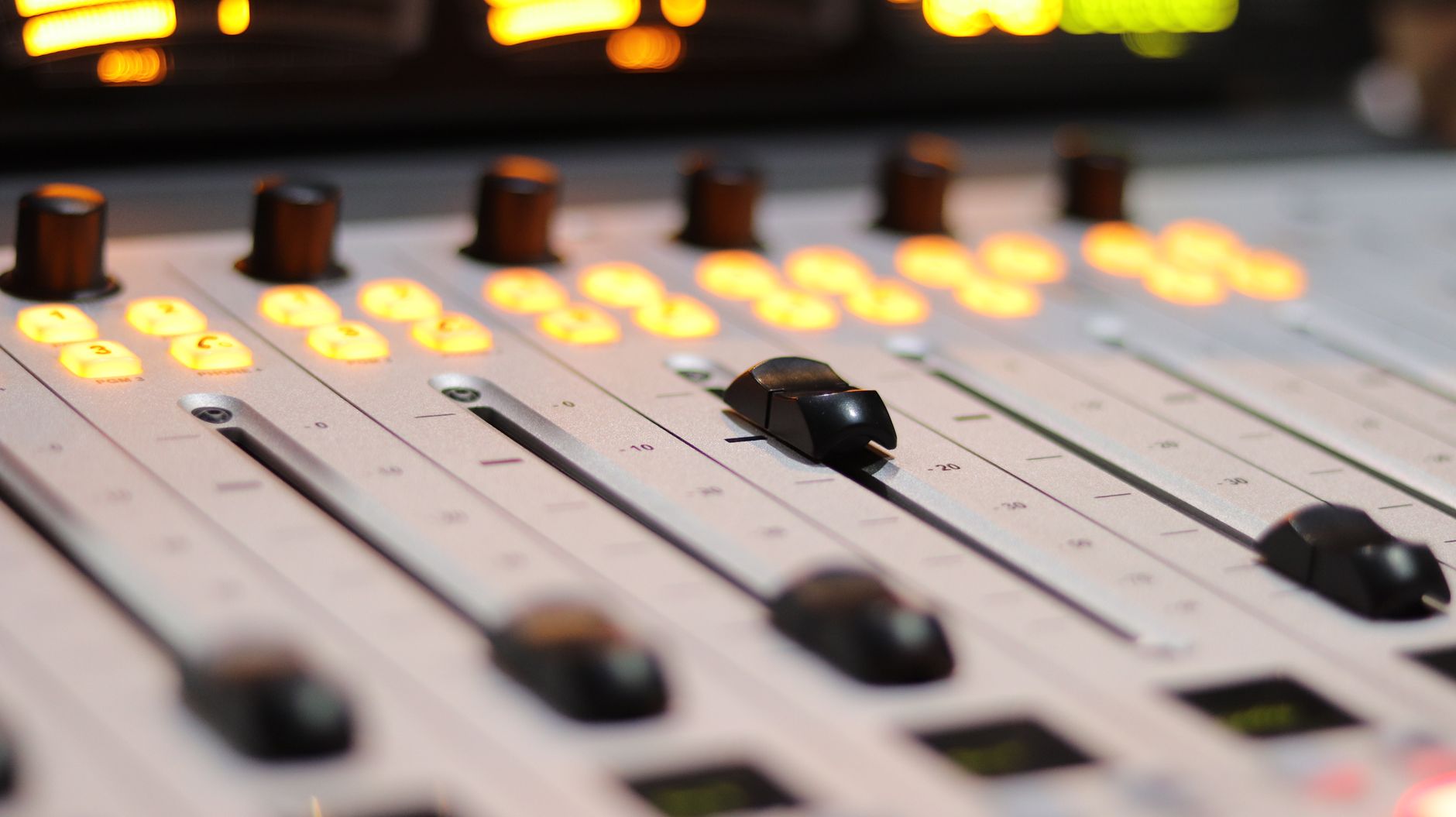 Âm thanh Analog vs Digital khác nhau thế nào - A detailed close-up of an audio mixer with vibrant, glowing controls in a studio setting.